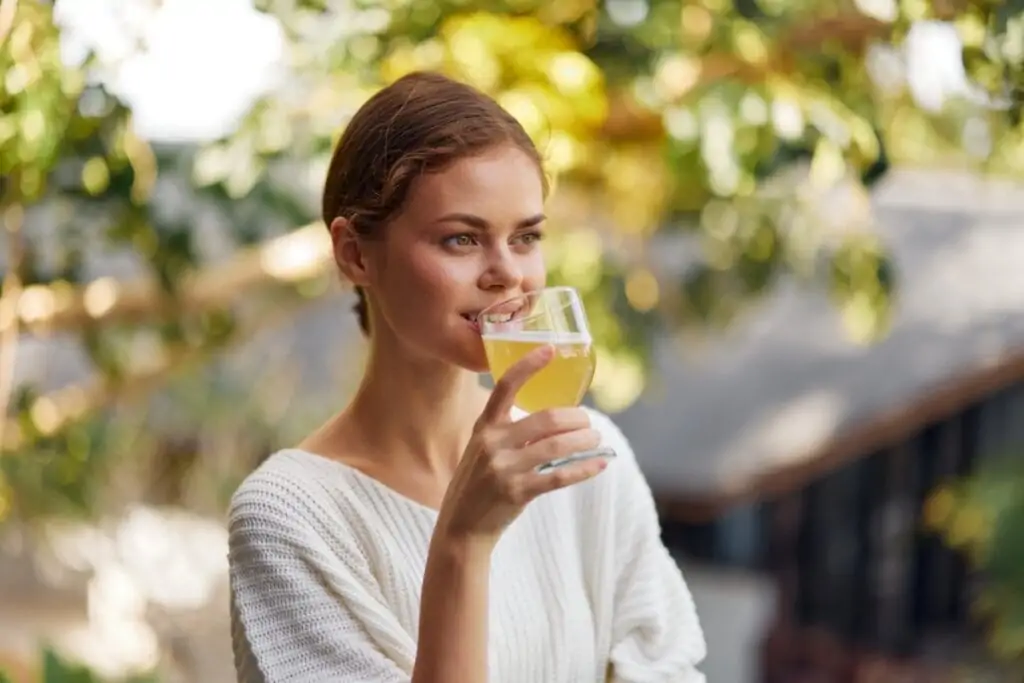 Mulher ao ar livre tomando kombucha em um copo de vidro 