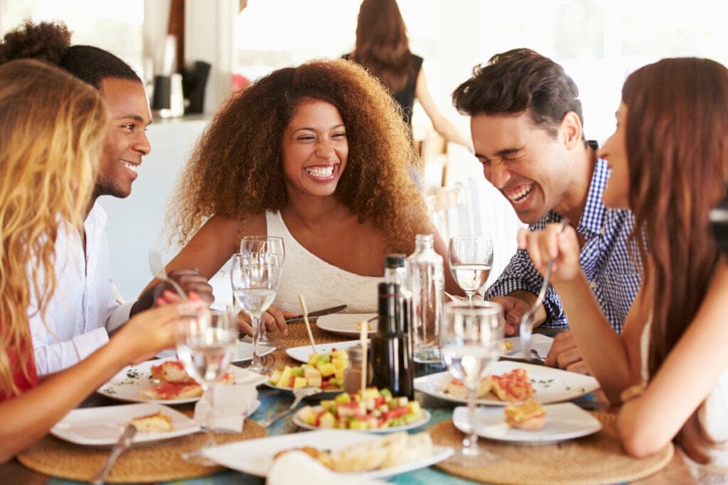 Pessoas sentadas em uma mesa comendo e sorrindo