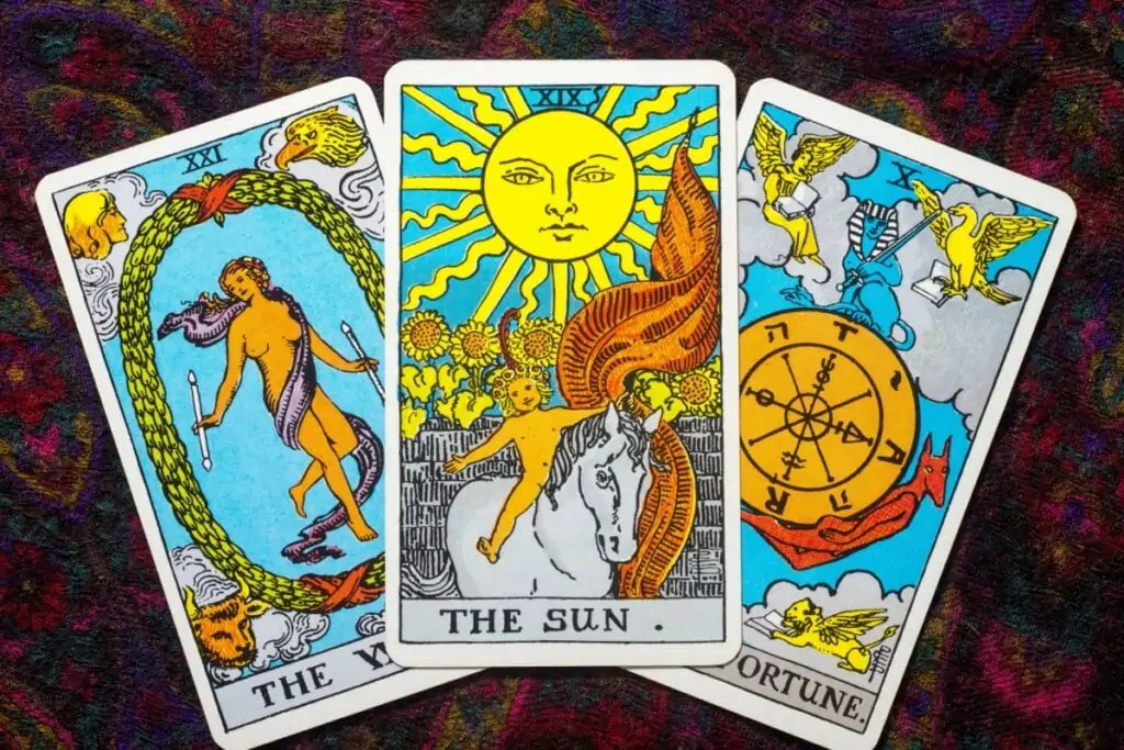 três cartas de tarot, com carta do Sol no centro