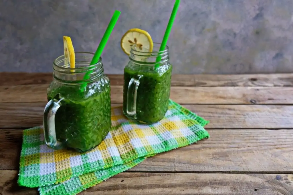 Dois copos de vidro com suco verde, rodela de limão-siciliano e canudo verde