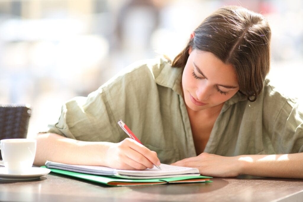Jovem mulher escrevendo em caderno