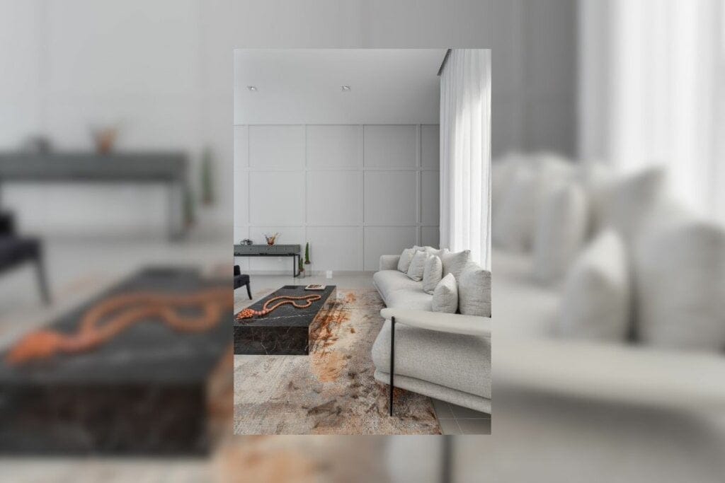 Sala de estar com parede revestida com boiseries, janela na lateral direita com cortina branca, sofá branco, mesa de centro preta e tapete bege felpudo