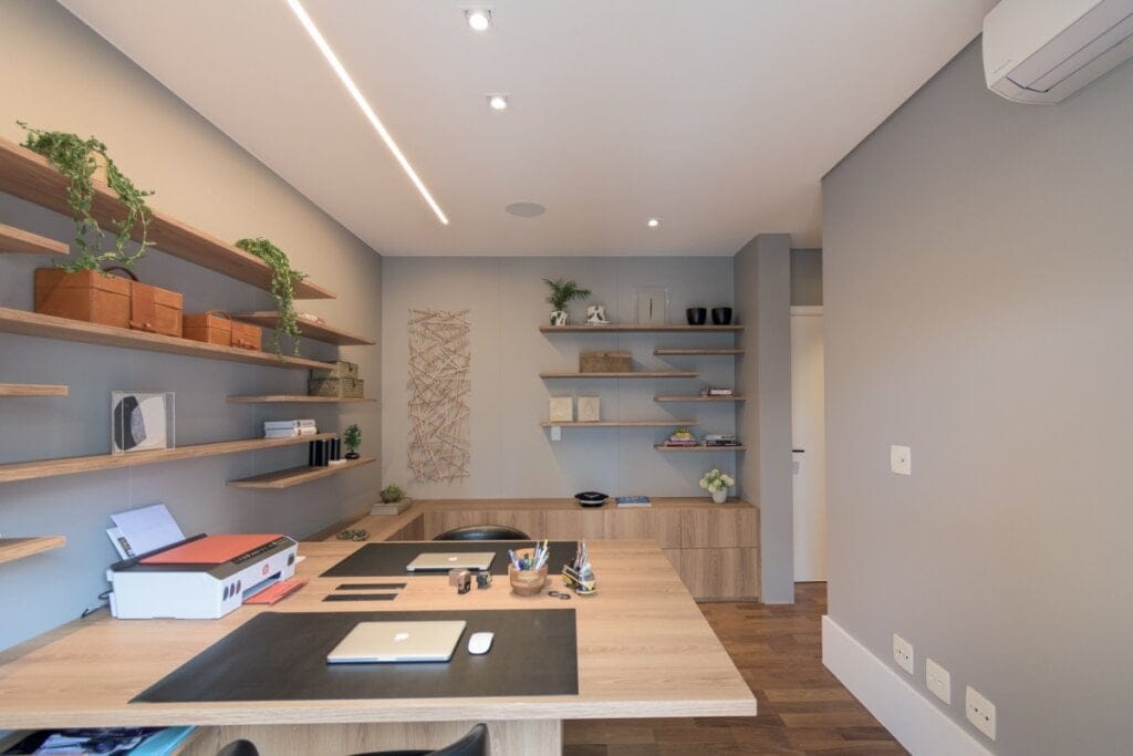 Escritório contemporâneo com mesa em madeira clara, prateleiras abertas e iluminação em trilho embutido no forro