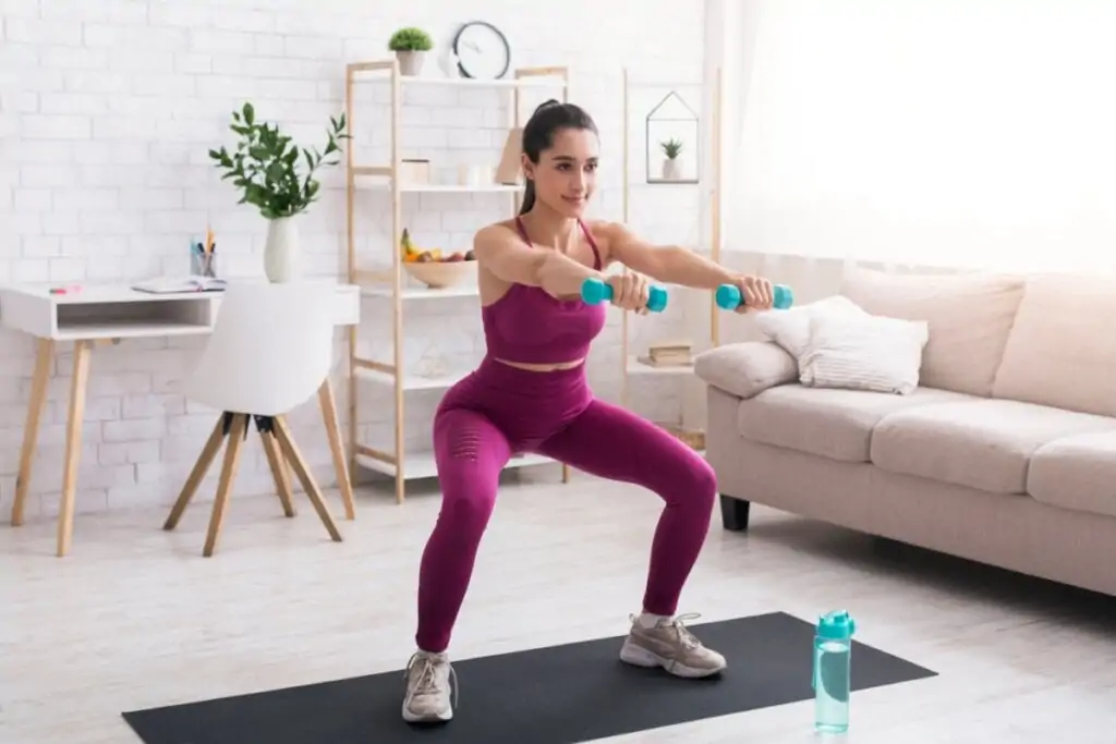 Mulher fazendo exercício de agachamento com halter na mão.