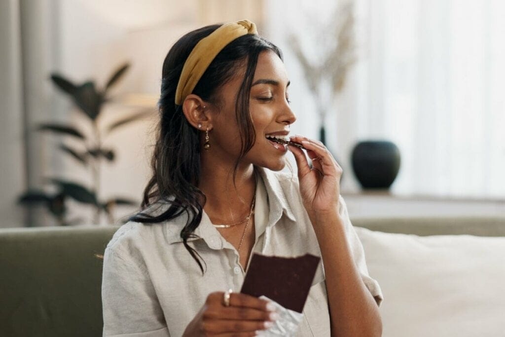 Mulher sorrindo comendo chocolate