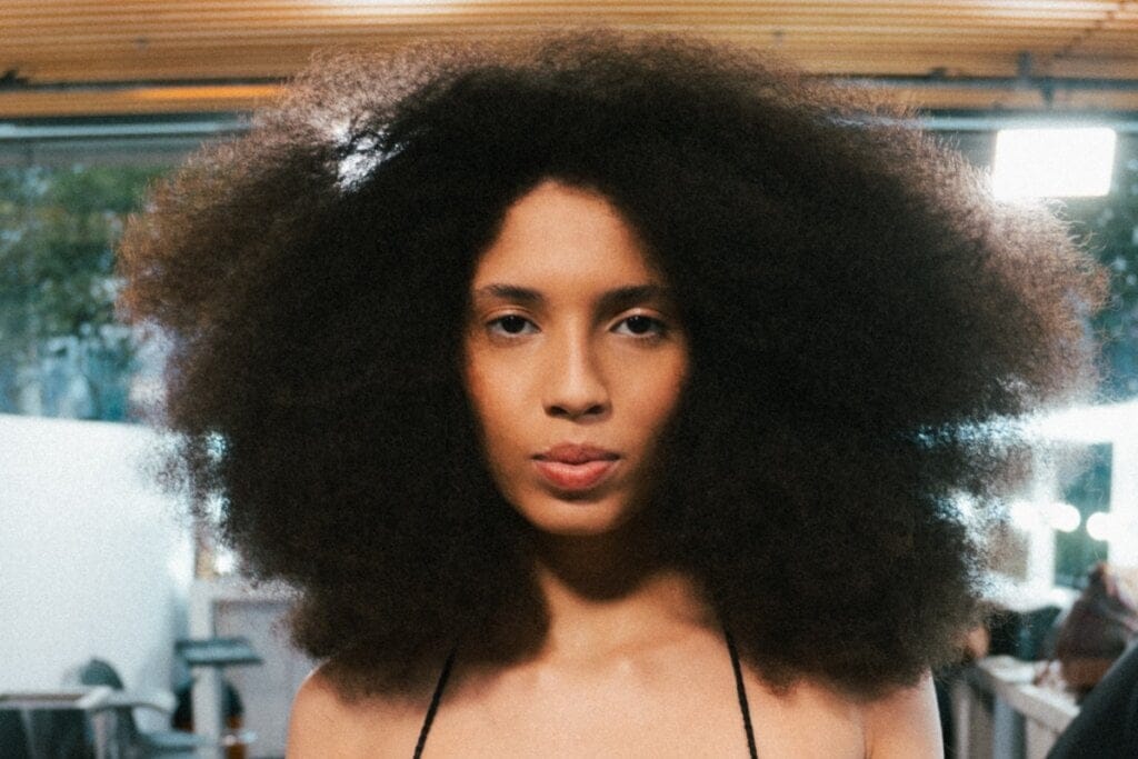 Mulher com cabelo afro volumoso olhando para foto