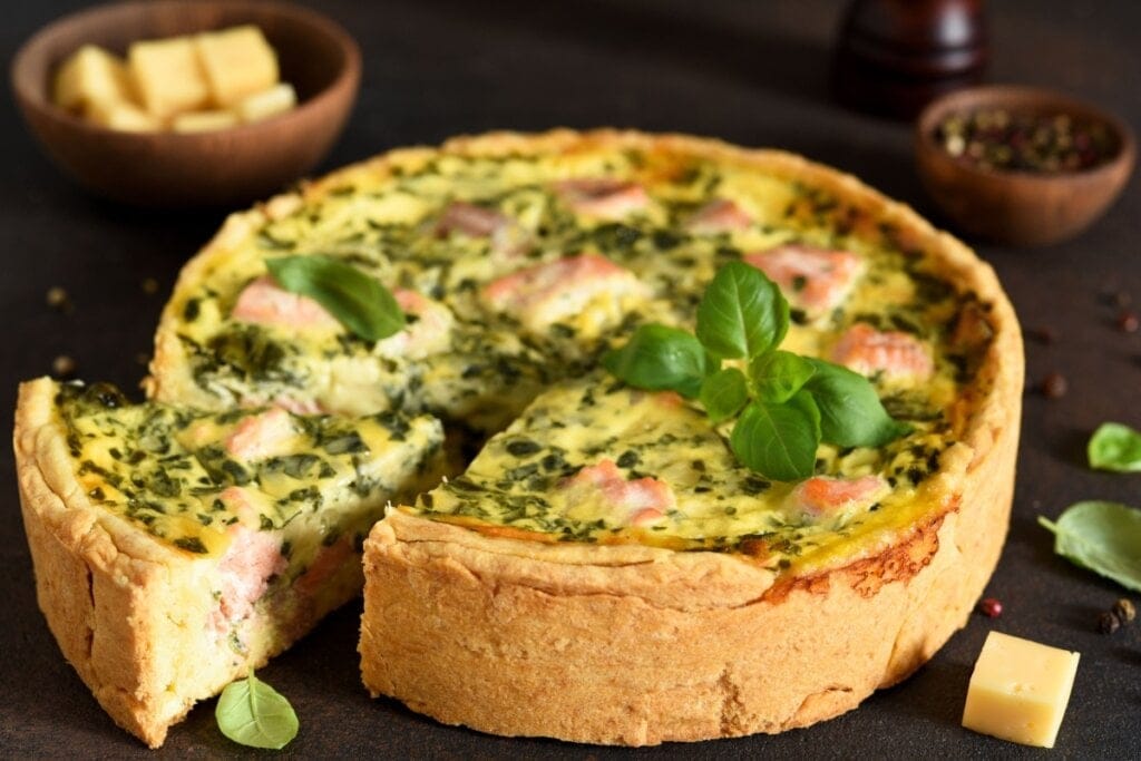 Quiche de salmão com espinafre servido em cima de mesa de madeira