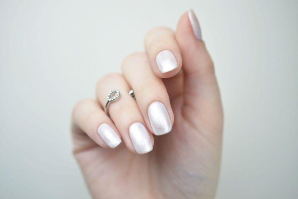 Mão com unhas prateadas peroladas