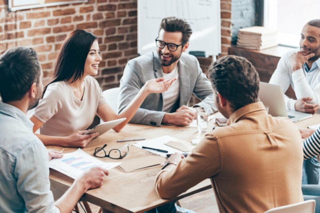 Pessoas sentadas ao redor de uma mesa de reunião conversando