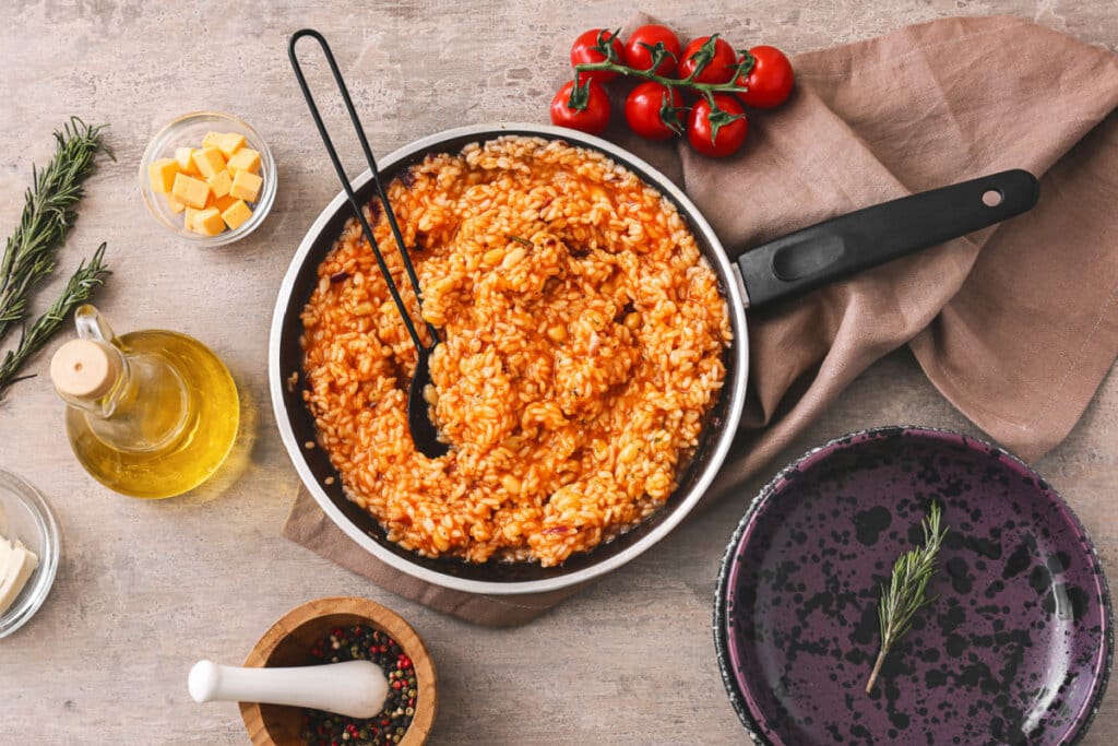 Frigideira com risoto de tomate e outros itens sob a mesa