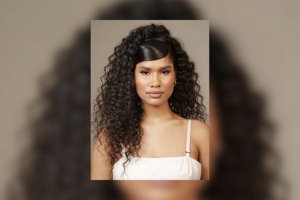 Mulher com cabelo semi preto. Franja lisa e fios cacheados soltos 