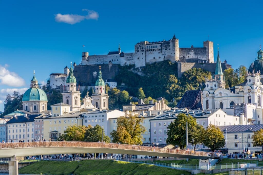 Imagem de um castelo no alto de uma montanha e rodeado por construções em Salzburgo