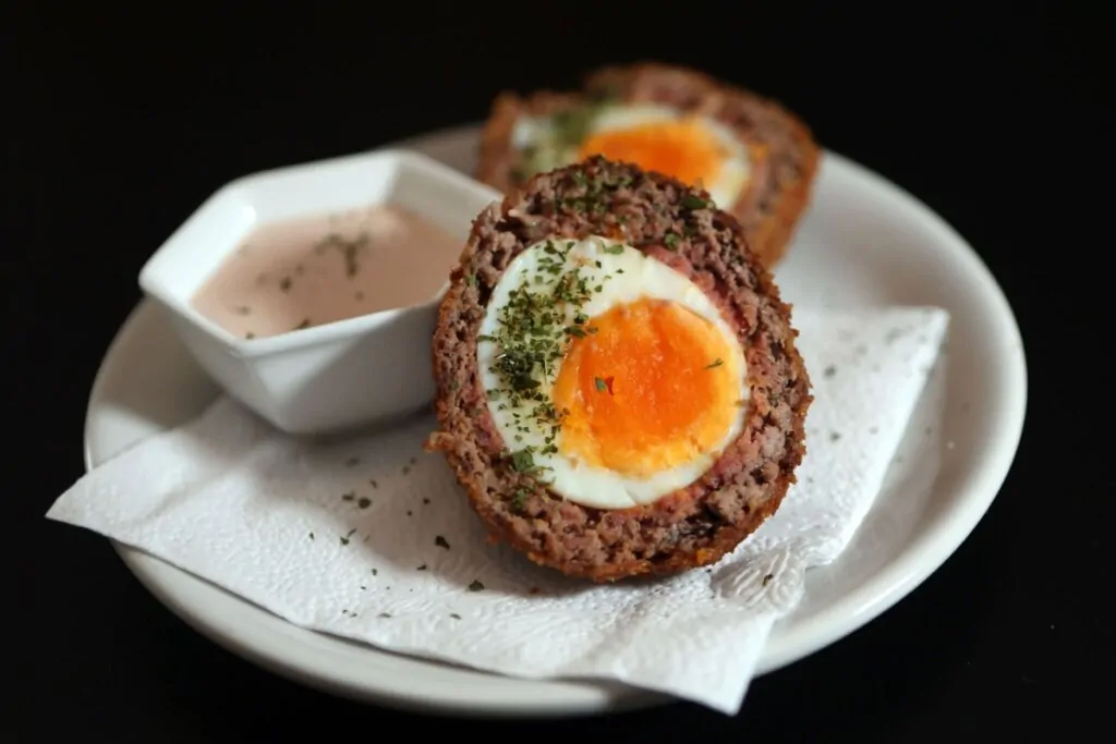 Bolovo cortado ao meio em prato de porcelana branco e ao lado tigelinha com molho rosé 