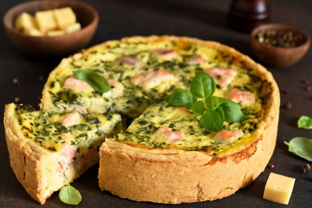 Quiche de salmão e espinafre servido em cima de mesa de madeira