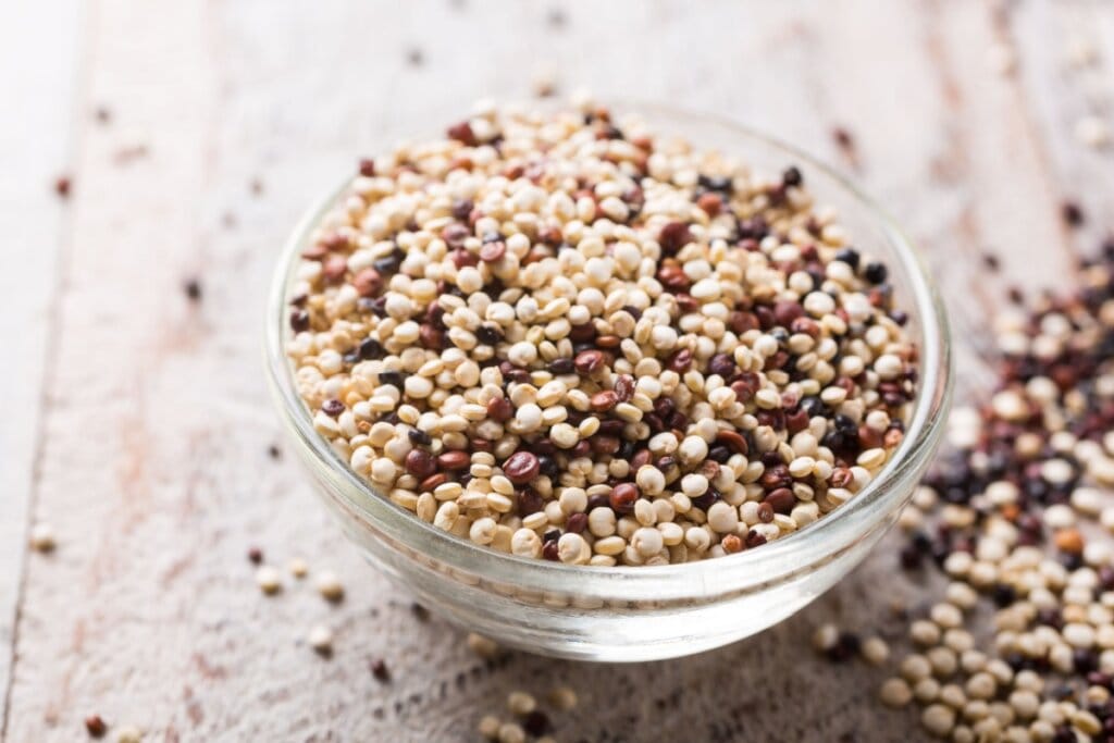 quinoa em pote de vidro em cima de mesa de madeira