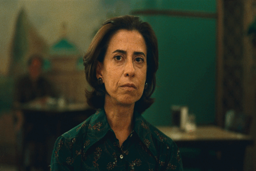 Imagem de uma mulher com cabelo liso, curto, usando uma camisa de botões verde com uma expressão triste em fundo escuro