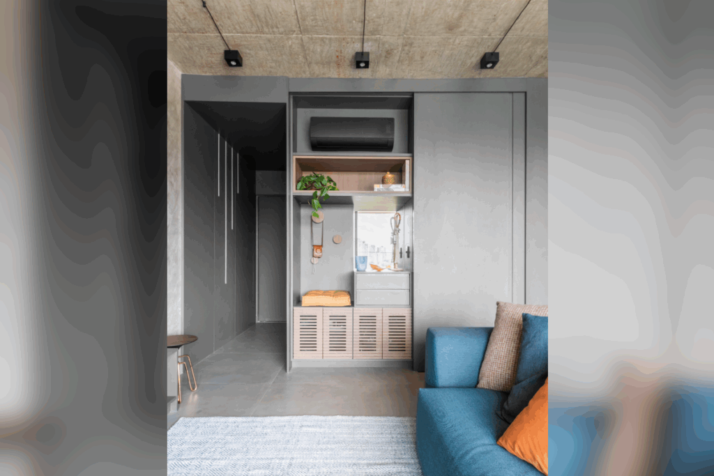 Sala com armários em madeira na cor cinza e parede na cor cinza, com sofá azul e almofadas em azul, laranja e cinza e piso cinza