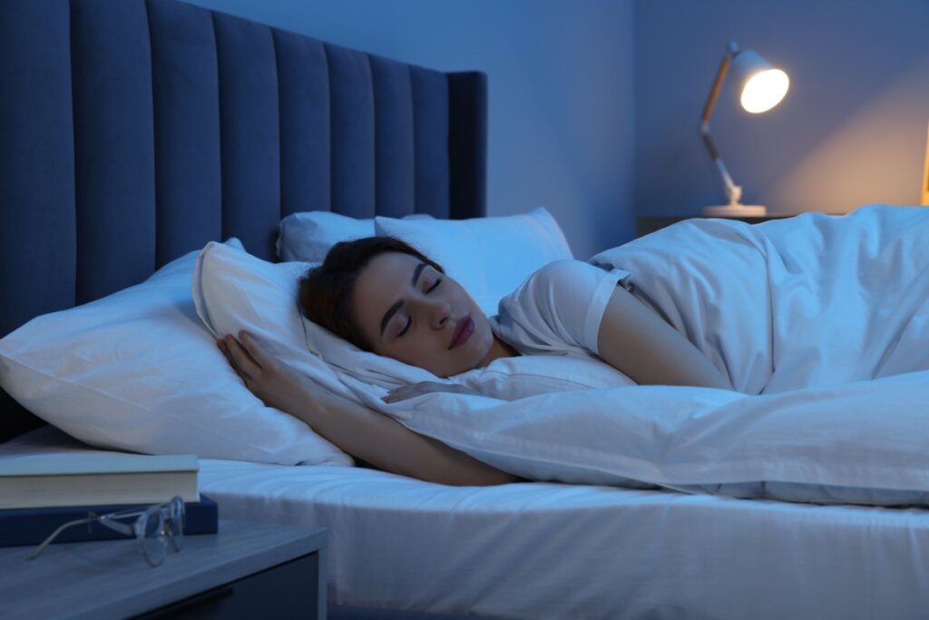mulher deitada e dormindo em cama branca com travesseiro e lençol branco