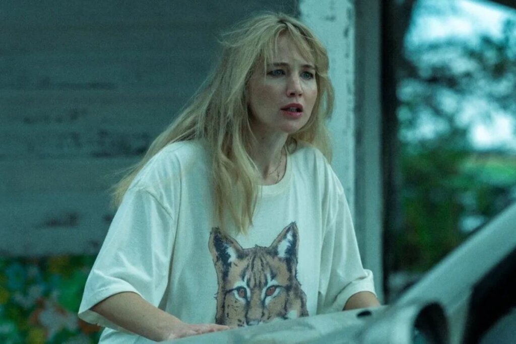 Jennifer Lawrence usando blusa branca e com o cabelo loiro bagunçado em cena do filme "Morra, Amor"