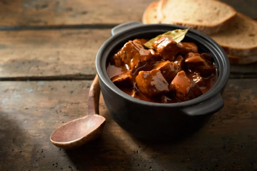 Carne de panela com cerveja preta em uma panela preta sobre uma mesa de madeira 