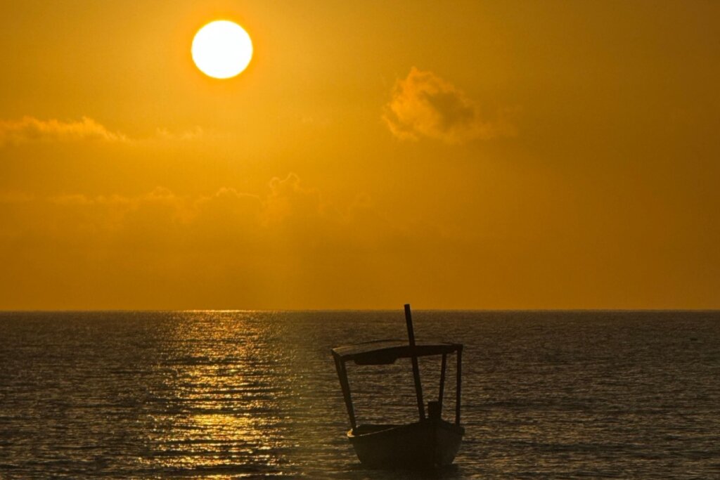 Pôr do sol na Ponta do Corumbau com um barco no mar
