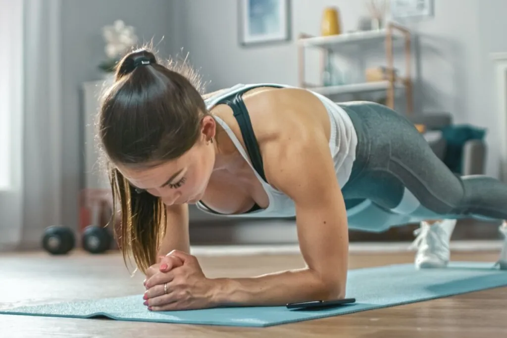 Mulher fazendo o exercício de prancha na sala de casa