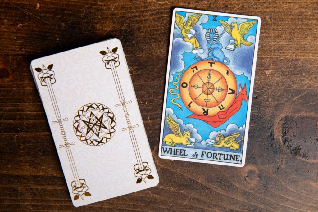Cartas de tarot em cima de mesa de madeira, com a carta da Roda da Fortuna em destaque