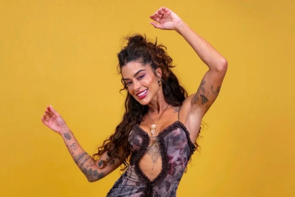 Aline Campos posando para foto em frente a um fundo amarelo