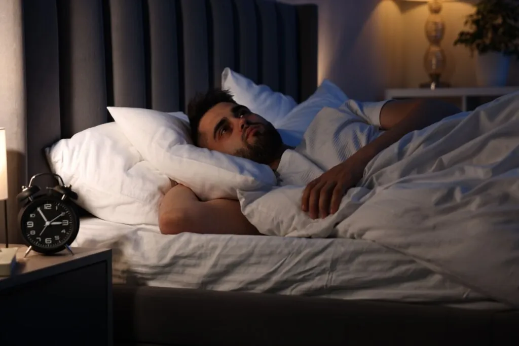 Homem deitado em uma cama e olhando para o teto 