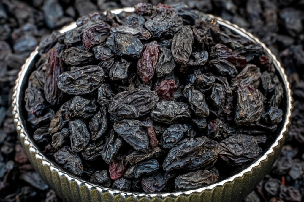 pote de metal com diversas uvas-passas pretas