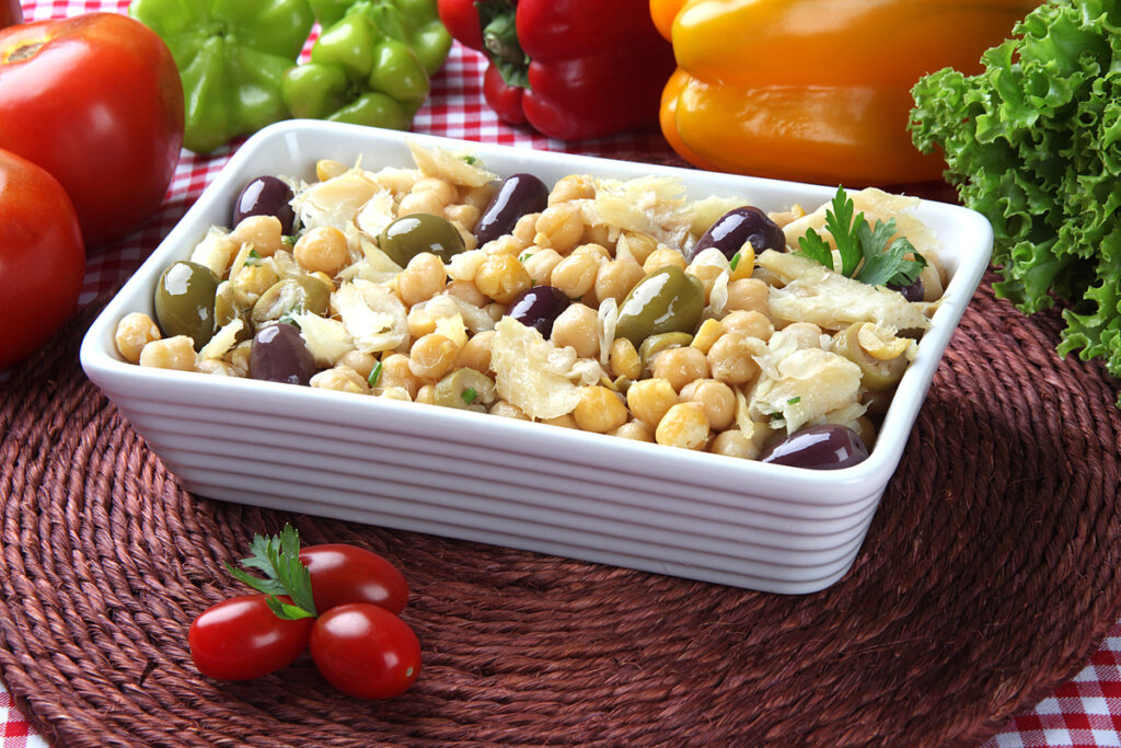 Recipiente branco com salada de grão-de-bico com bacalhau e azeitonas