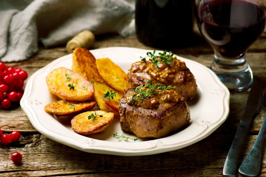 Filé-mignon com molho de mostarda, acompanhado de batatas douradas, servido em prato branco