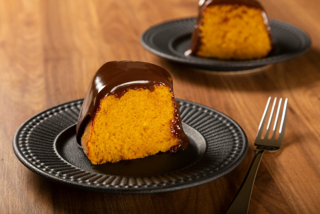 Pedaço de bolo de cenoura com chocolate em um prato preto
