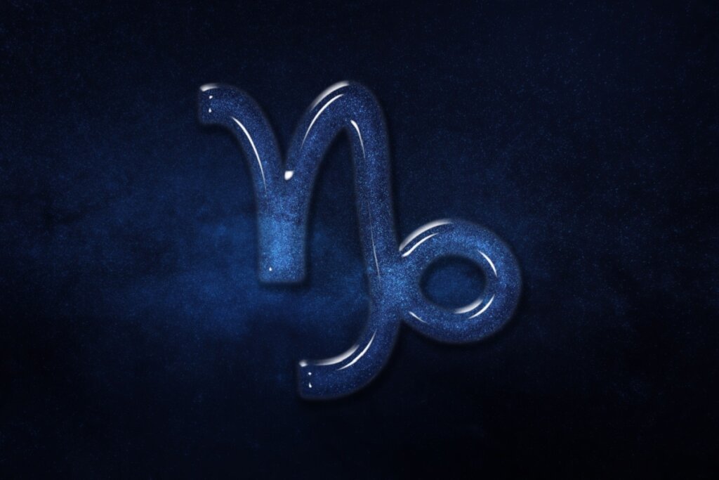 Símbolo de Capricórnio representado com um efeito de vidro brilhante preenchido por poeira estelar azul, sobre um fundo de céu noturno azul-escuro profundo e estrelado.