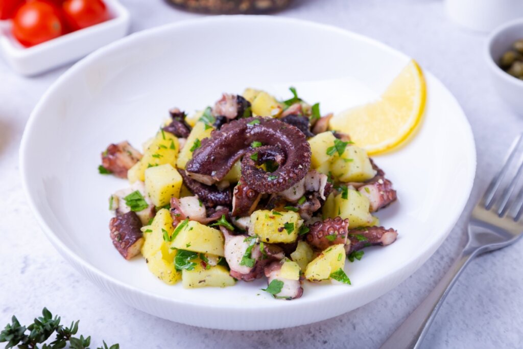 Polvo com batatas em prato fundo branco