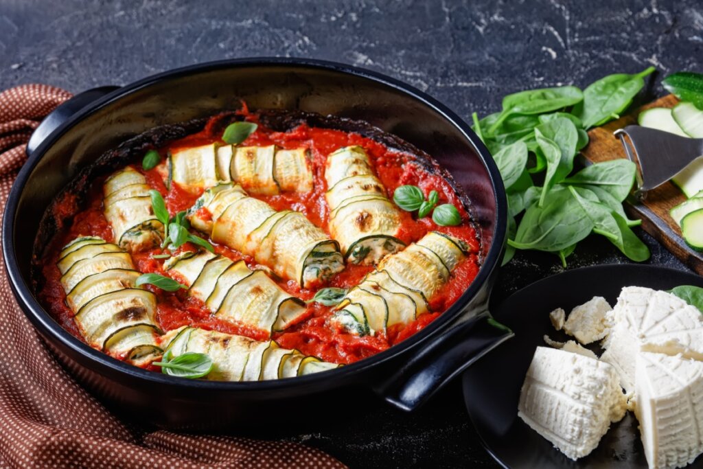 Canelones de abobrinha com tofu e espinafre em uma panela preta com molho de tomate 