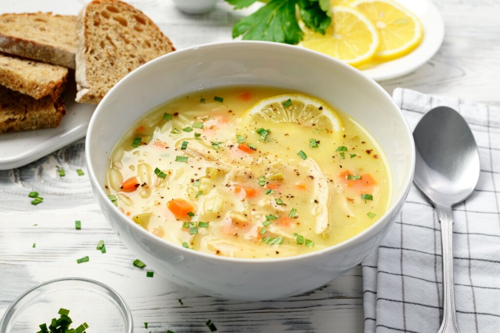 Recipiente banco com sopa de frango com limão, legumes e orzo