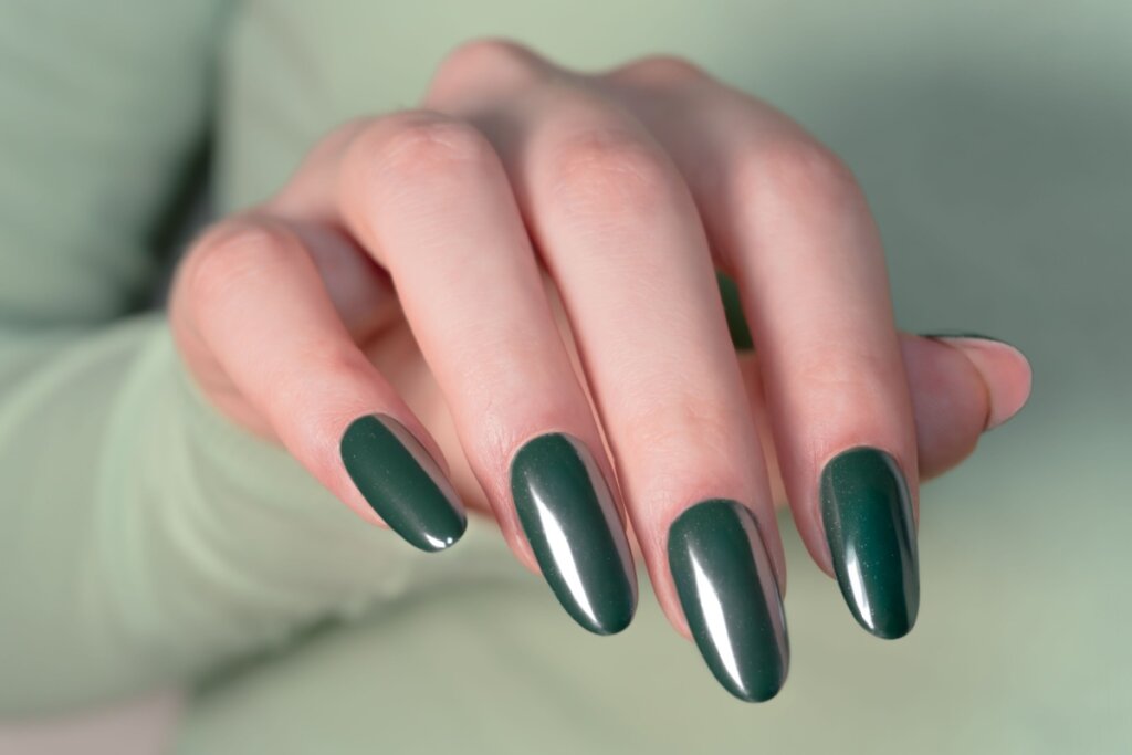 Mãos com unhas longas pintadas com esmalte verde-escuro