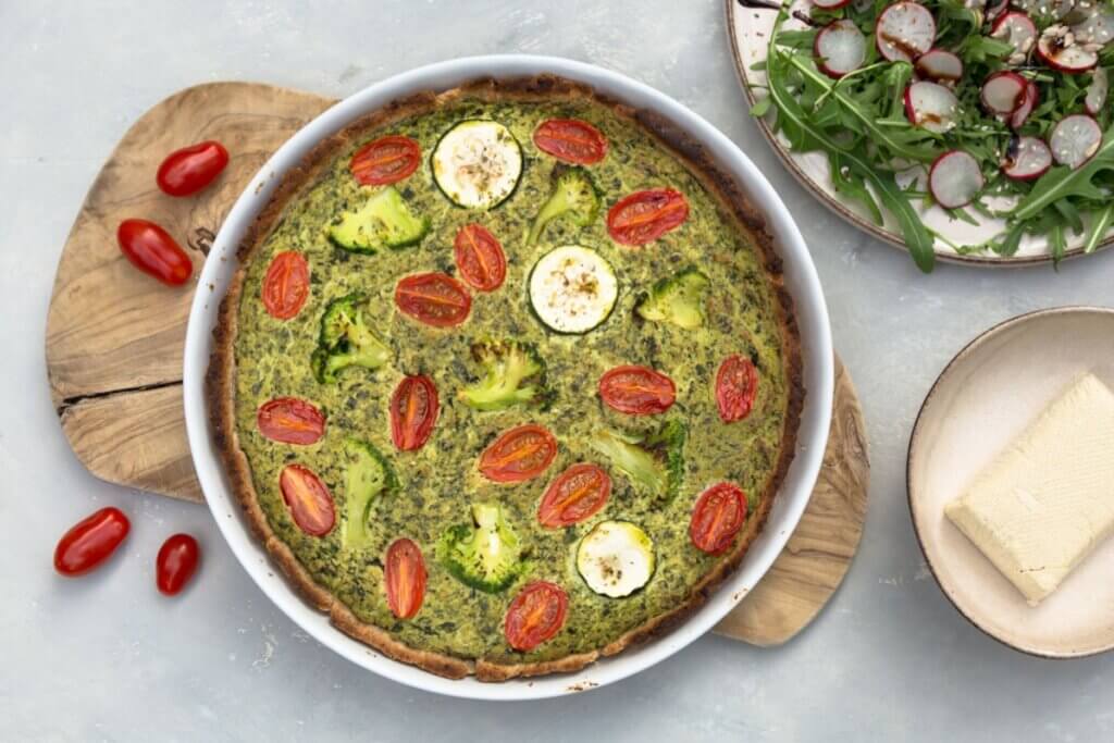 Travessa branca com quiche de brócolis com tomate e tofu