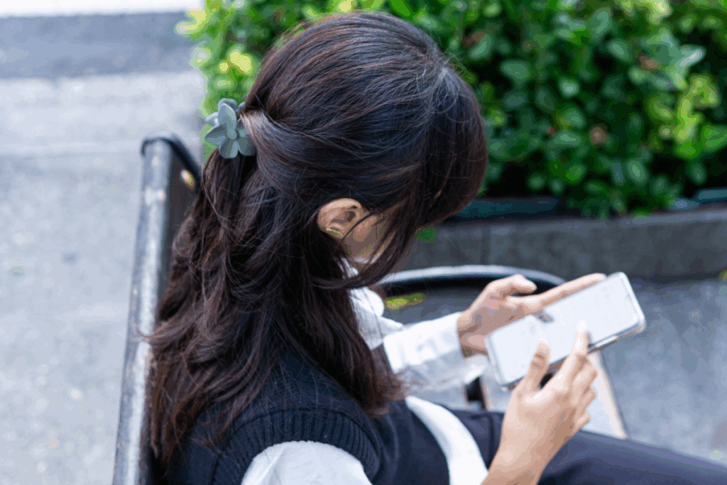 Mulher de cabeça baixa exibindo o cabelo meio preso com uma presilha verde em formato de flor