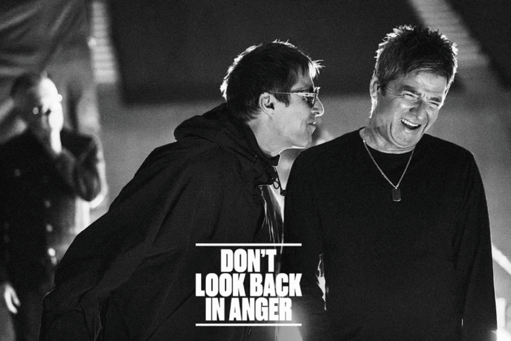 Em registro em preto e branco, dois homens aparecem sorrindo e conversando nos bastidores, enquanto o título Don't Look Back in Anger é destacado na parte inferior da imagem em branco.